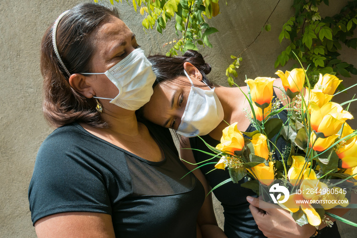 Women mourning those lost to the coronavirus, wearing face masks, showing mutual support, hugging