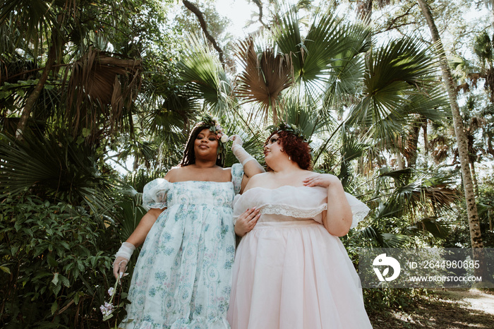 2 plus size women stand together talking in the tropical forest