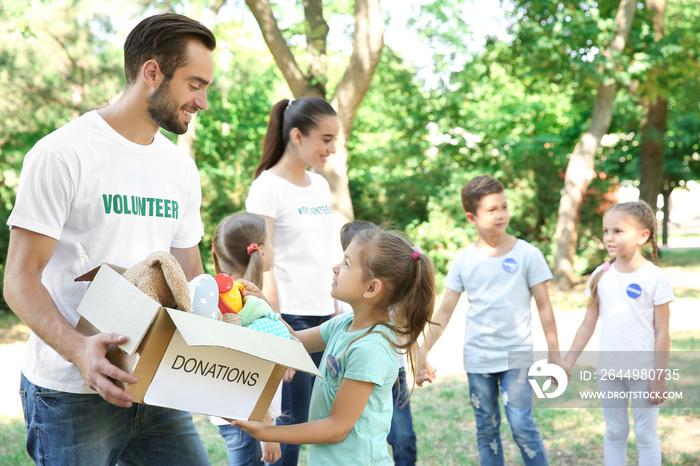 Young volunteers and children with box of donations outdoors