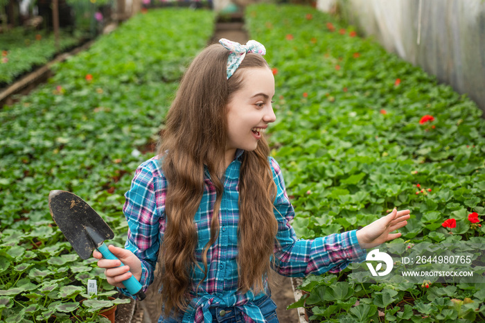 surprised happy teen girl florist care pot plants in greenhouse, gardener