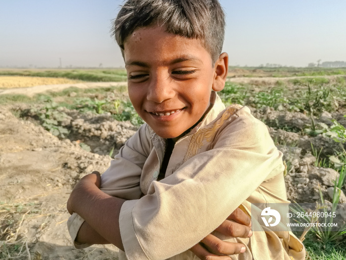 a poor cute smiling boy in a village wearing recycled used clothes