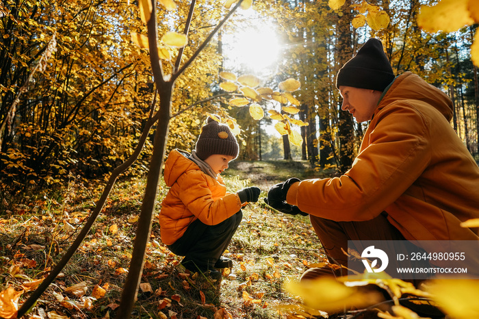 Father and son having fun in autumn forest.