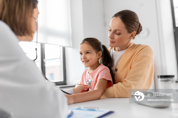 medicine, healthcare and pediatry concept - mother with little daughter and doctor with stethoscope at clinic