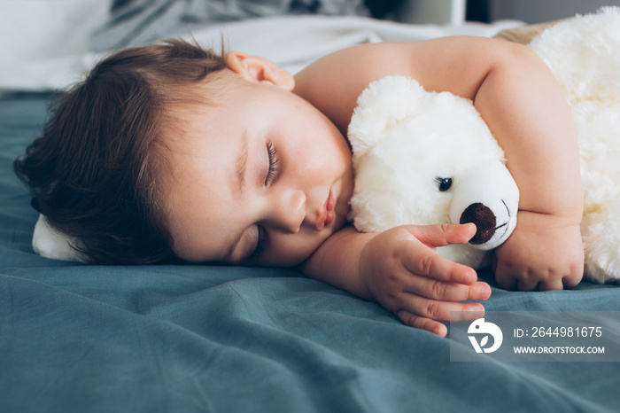 Beautiful baby sleeping with his teddy bear aside, family concept