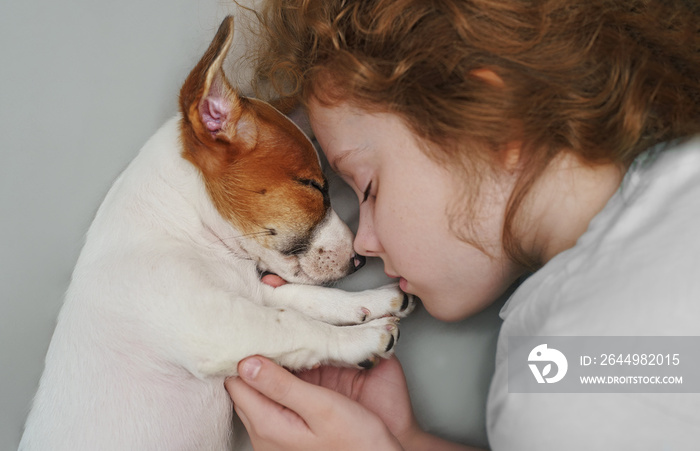 Sweet curly girl and puppy jack russell dog is sleeping in night.