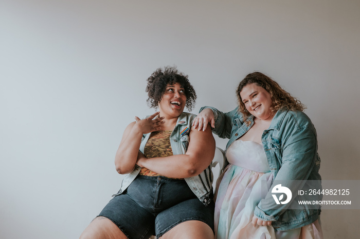 portrait of 2 plus size friends smiling and laughing