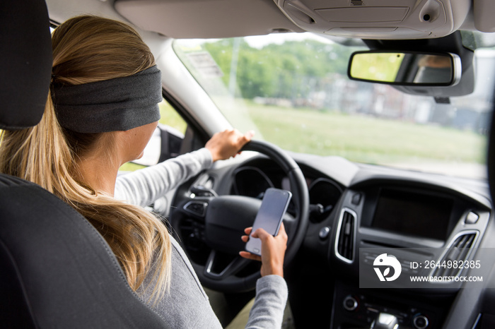 Junge Frau mit verbundenen Augen am Steuer eines Autos