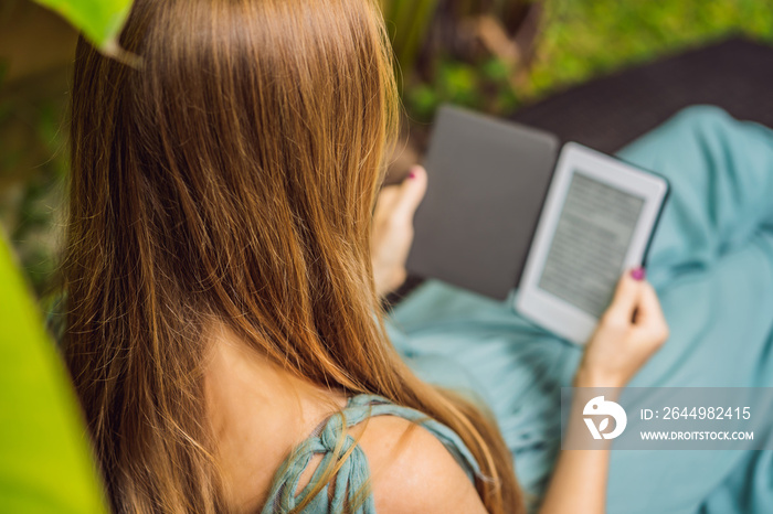 Woman reads e-book on deck chair in the garden