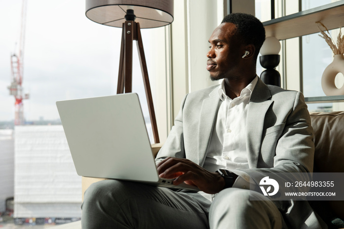 Young businessman sitting on sofa and using laptop