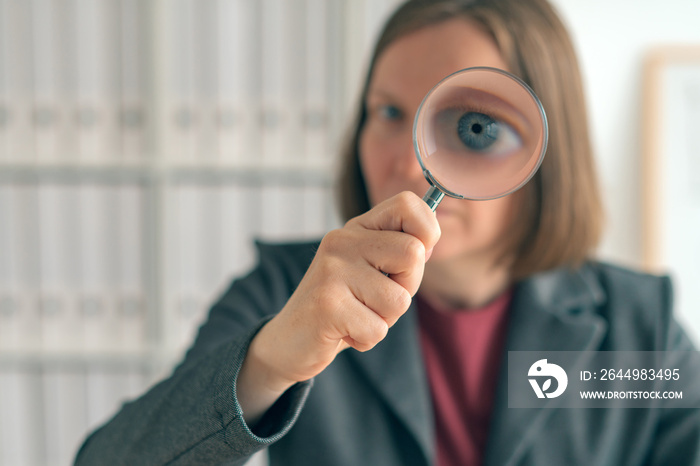 Businesswoman with magnifying glass doing business financial auditing