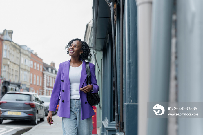 Smiling woman in purple jacket walking in city