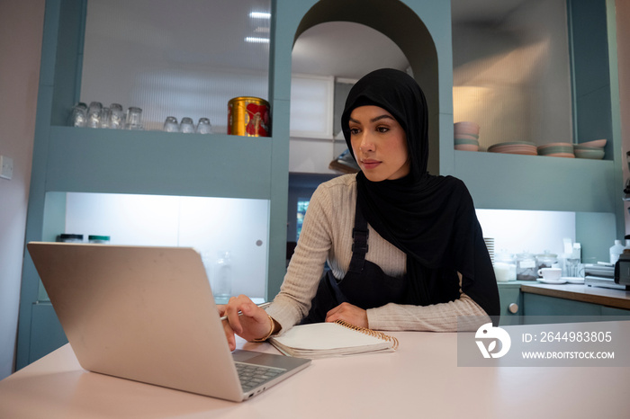 Female cafe owner working on laptop