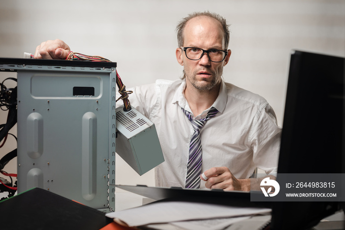 Portrait of desperate office worker trying to fix broken computer