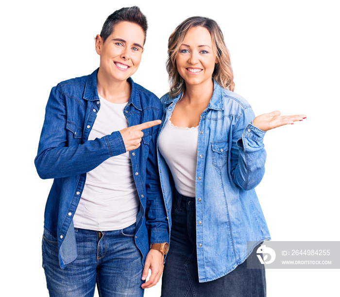 Couple of women wearing casual clothes amazed and smiling to the camera while presenting with hand and pointing with finger.