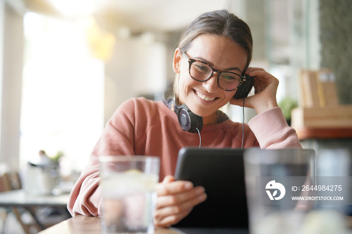 Young woman inside an urban space with headphones and devices