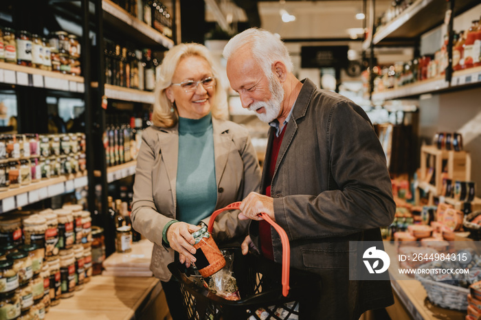 Happy senior couple shopping in grocery store or supermarket. Consumerism concept.