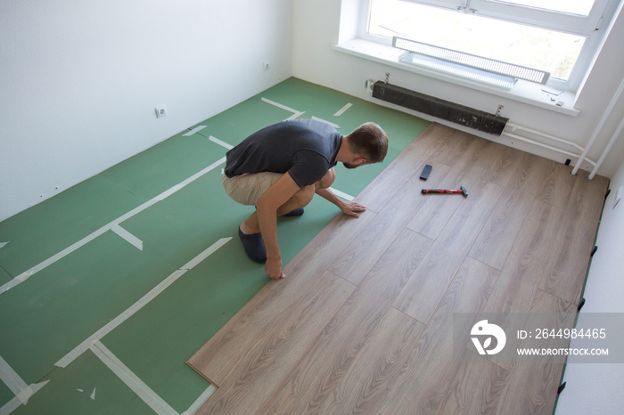 male foreman lays laminate flooring in the room, renovation concept