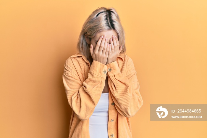 Young blonde girl wearing casual clothes with sad expression covering face with hands while crying. depression concept.