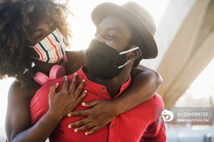 African couple having fun outdoor wearing face masks during Coronavirus outbreak - Covid 19 people lifestyle and love concept - Focus on man’s eye