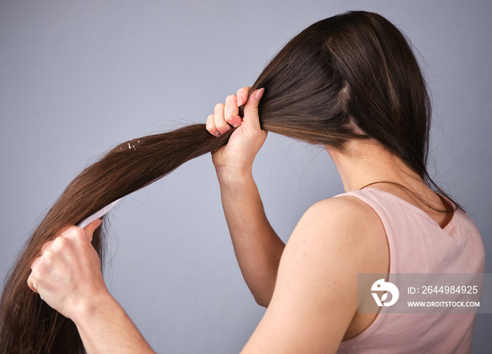 back view Brunette Young woman combing pulls wet and tangled hair after shower