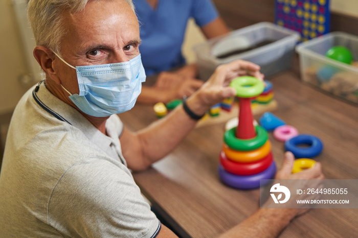 Mature man on therapy after suffering from stroke in rehabilitation room