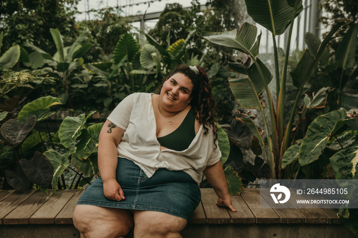 plus size woman sits on bench smiling