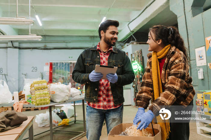 Indian man with tablet and woman working at recycling station