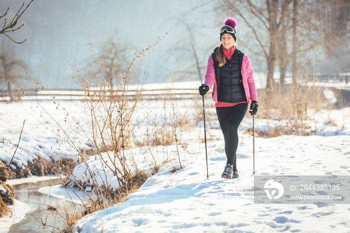 Woman on the trail for a winter hike in sunny landscape