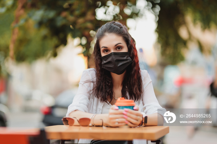 Quarantine rate in a cafe, a young woman in a black mask.