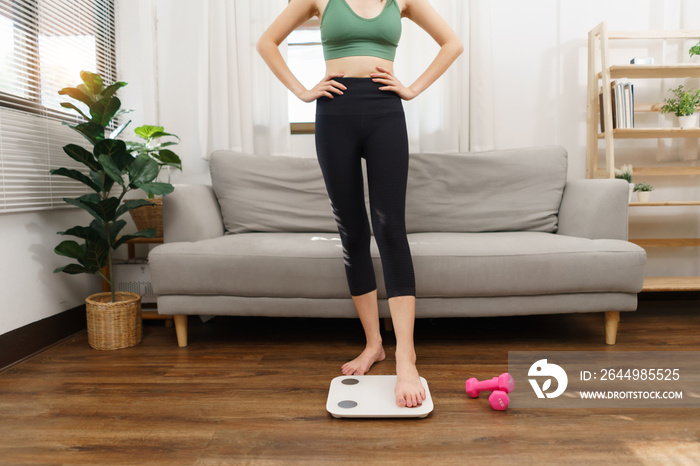 Healthy and weight loss concept, Young Asian woman stepping on weighing scales after weight control