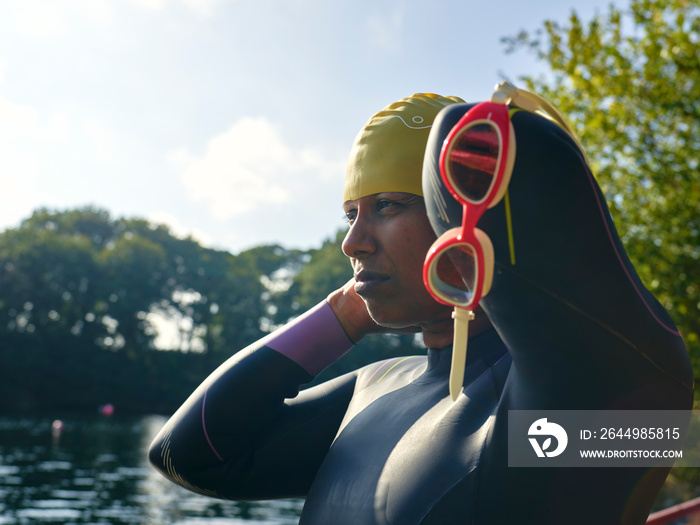 Woman in wetsuit putting on swimming cap