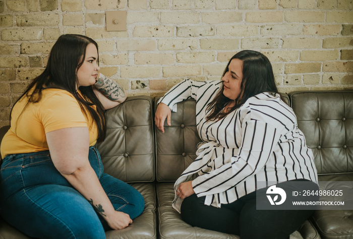 closeup of 2 women sitting on sofa chatting