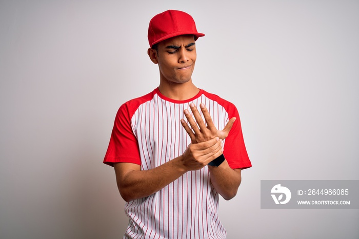 Young handsome african american sportsman wearing striped baseball t-shirt and cap Suffering pain on hands and fingers, arthritis inflammation