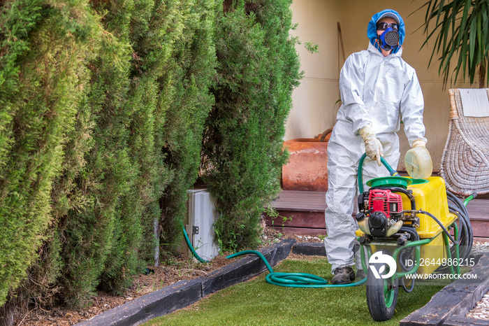 Fumigator with a motorized fumigation machine preparing fungicide and phytosanitary products for pest control and fertilizer of plants. The fumigator is wearing a protective suit against toxic product