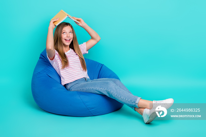 Full length photo of adorable dreamy girl dressed pink t-shirt bean bag looking book empty space isolated teal color background