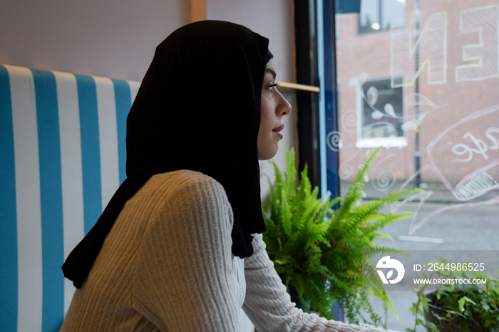 Young woman in hijab sitting in cafe