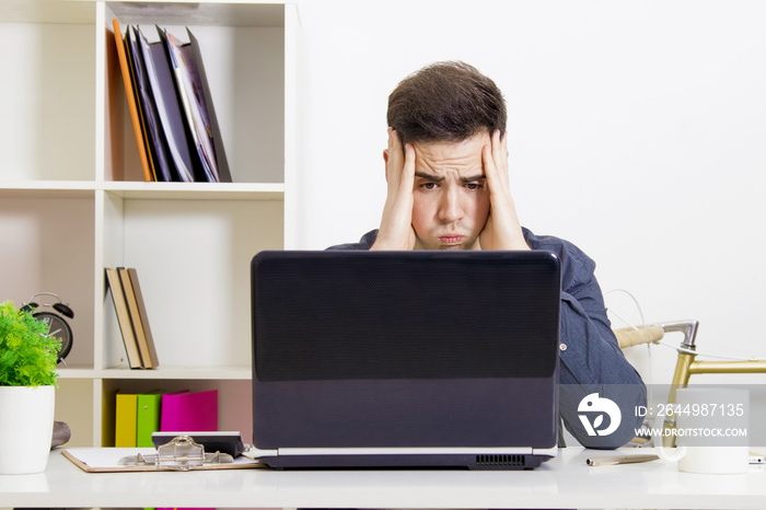 young man in front of the computer laptop concentrated or overwhelmed