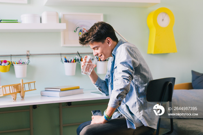 Teenage boy drinking water in his room