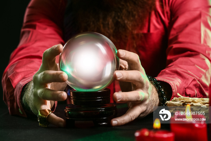 Male fortune teller with crystal ball at table, closeup