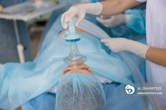 Close up hands of doctor anesthesiologist holding breathing mask on patient face during operation