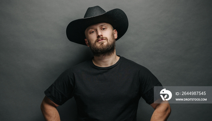 Handsome cowboy wearing black cowboy hat with beard