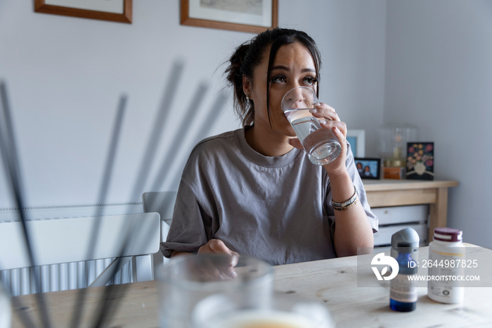 Woman drinking water from glass at home