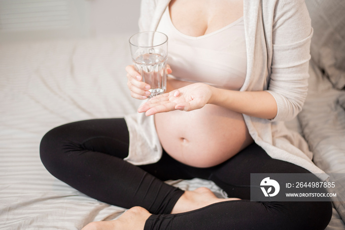 Close up pregnant woman eating vitamin pills