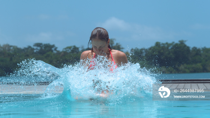 CLOSE UP: Girl pinches her nose and jumps into beautiful crystal clear water,