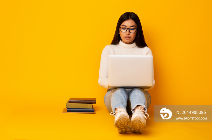 Student Girl Using Laptop Studying Over Yellow Studio Background