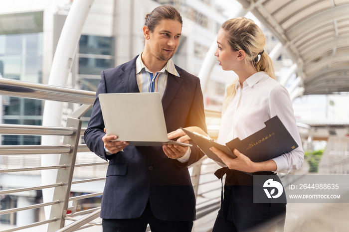 Two business people working and discussing online data in front of laptop