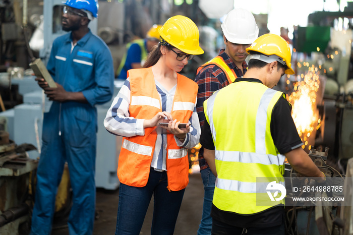 Quality control inspector checking workers at factory. Engineering Worker team working in Heavy Industry Manufacturing Facility.