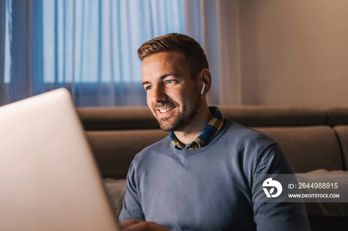 Data entry, software engineering, and remote business. A happy senior developer with earphones typing on his laptop code and trying out new technologies in software engineering while sitting at home.