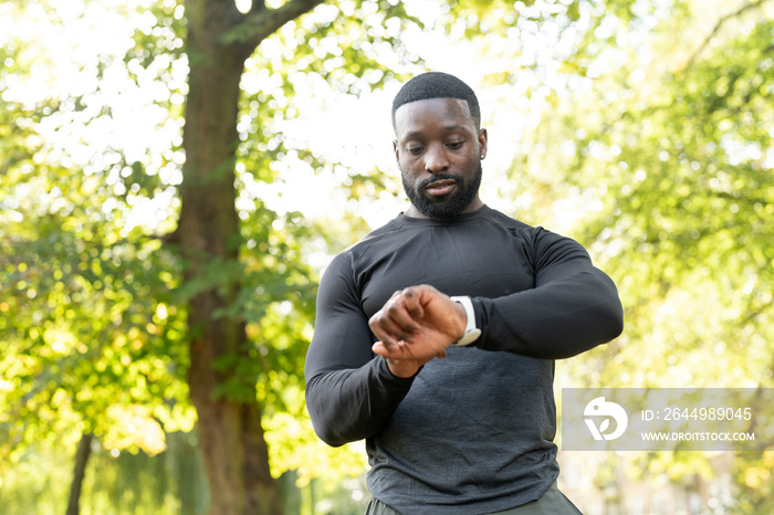 Athletic man checking smart watch in park