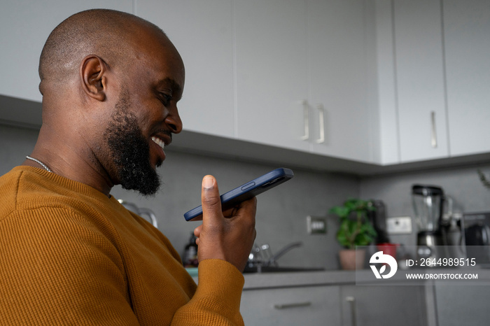 Smiling man using smart phone in kitchen